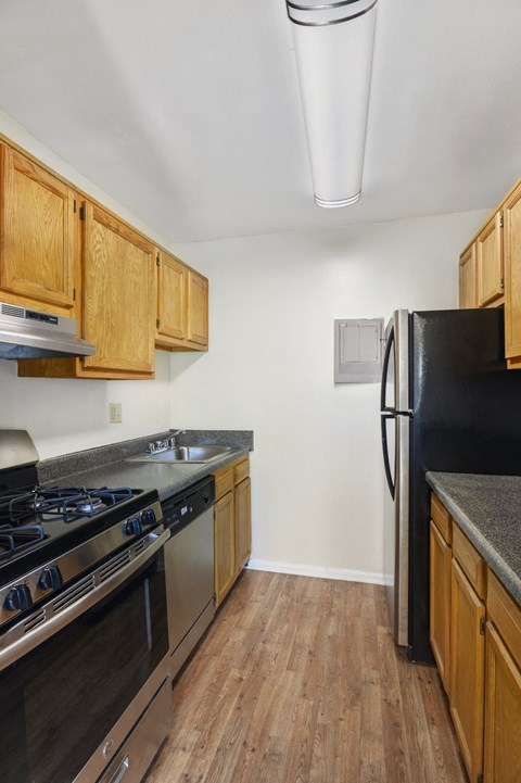A kitchen with wooden cabinets and a black refrigerator.