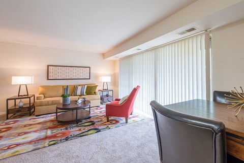A living room with a red chair and a grey desk.