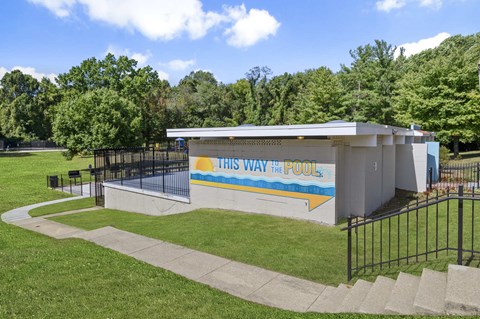 A pool building with the words "This Way to the Pool" on it.