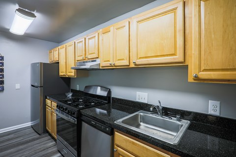 A kitchen with black countertops and wooden cabinets.