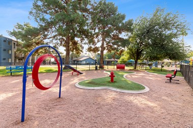 a playground with a red fire hydrant in the middle and trees in the background