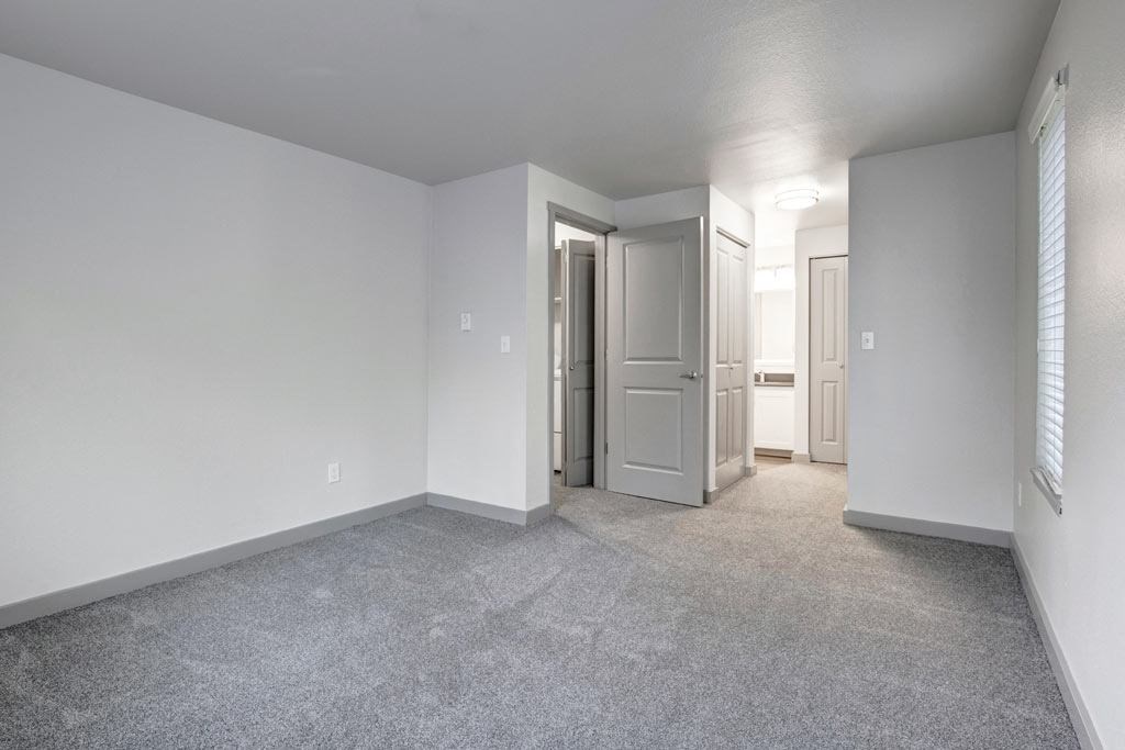 a bedroom with white walls and gray carpet