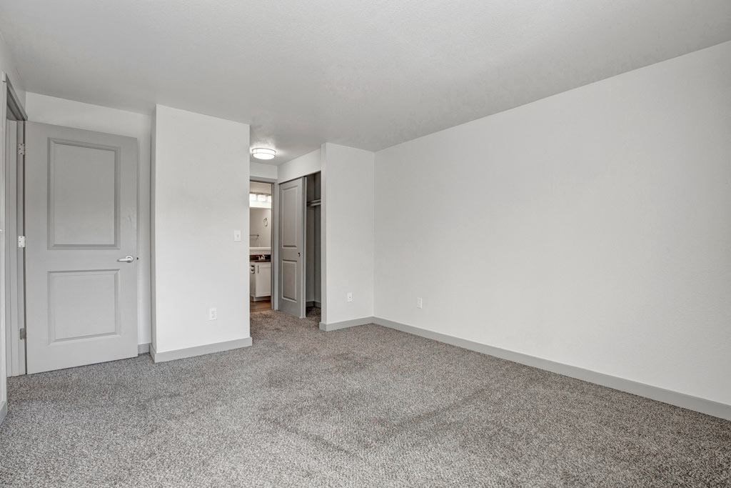 a bedroom with white walls and carpet