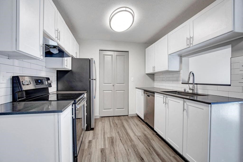 a kitchen with white cabinets and black counter tops