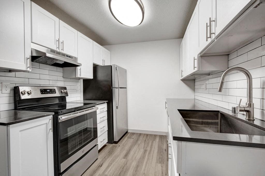 a kitchen with white cabinets and black appliances