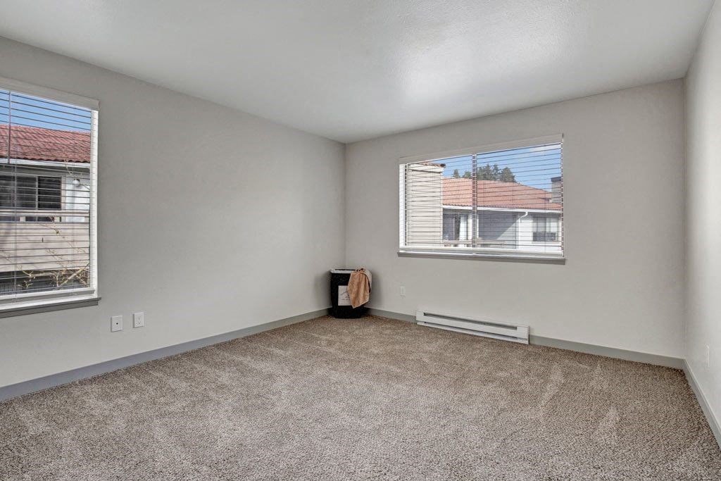 a bedroom with two windows and a carpeted floor