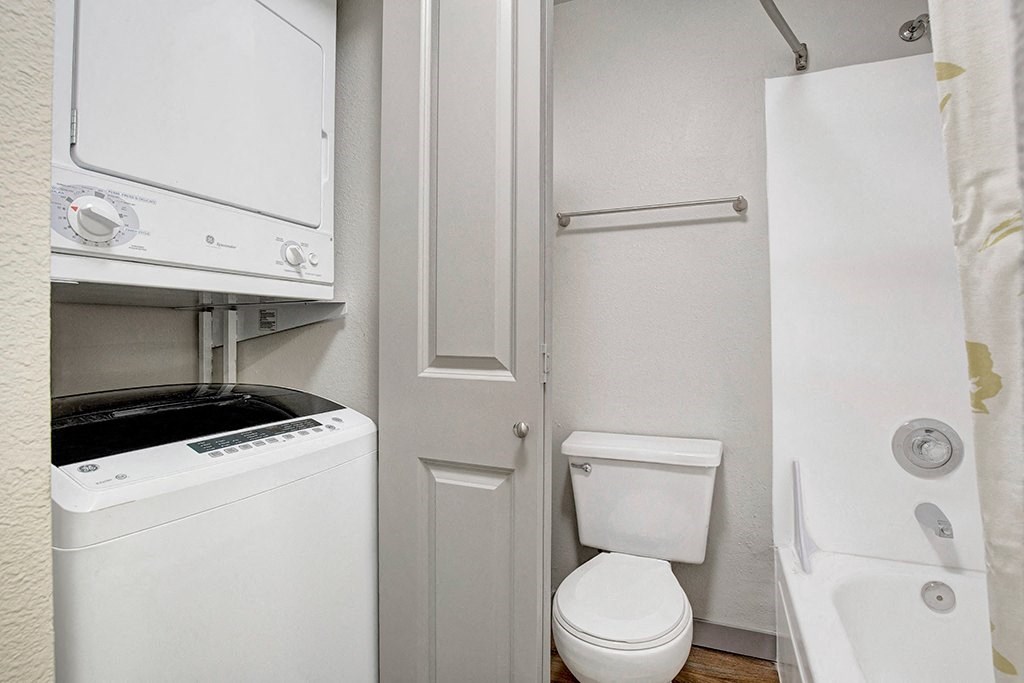 a bathroom with a washer and dryer and a toilet