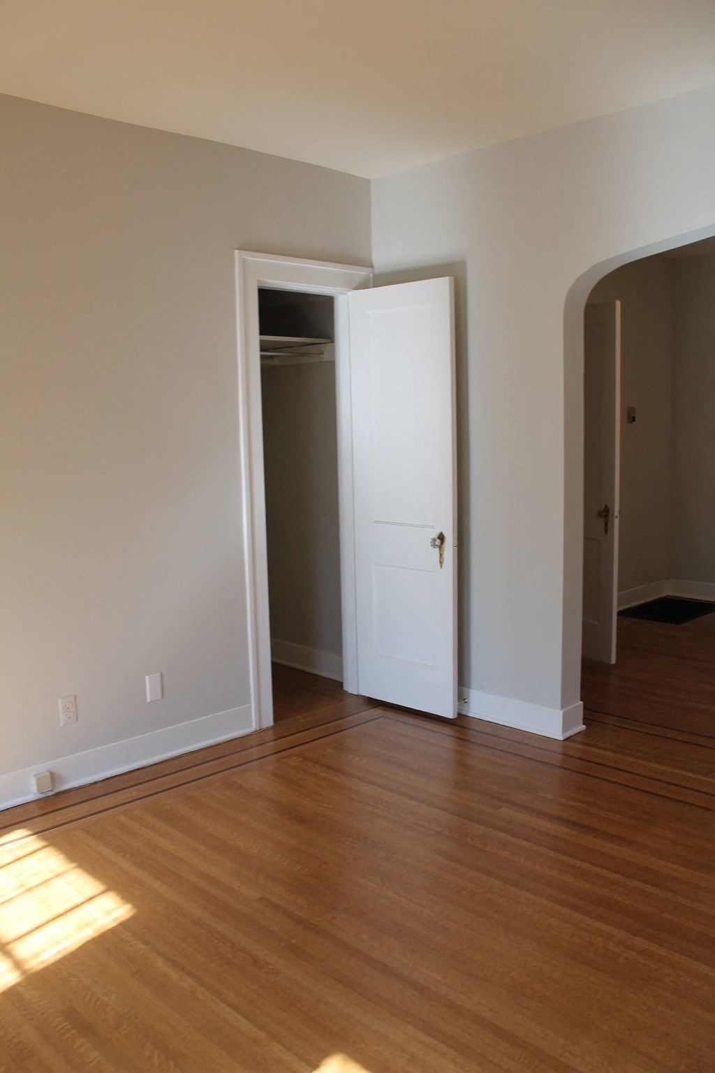 an empty living room with wooden floors and a white door
