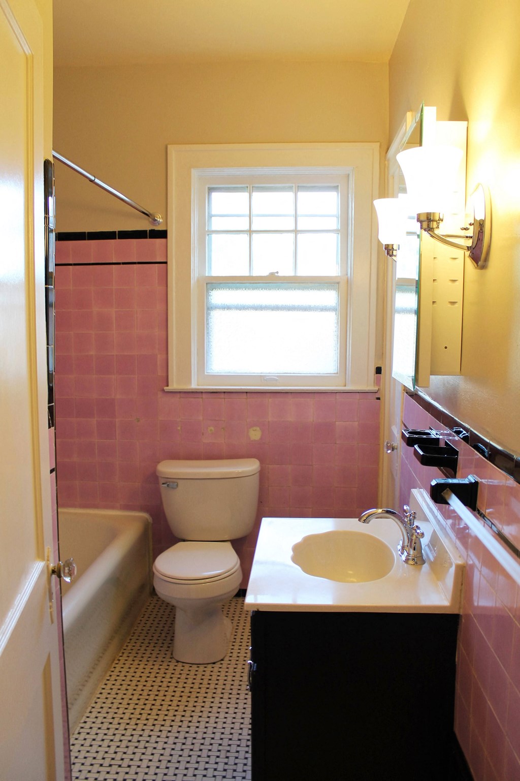 A bathroom with a toilet, sink, and window.
