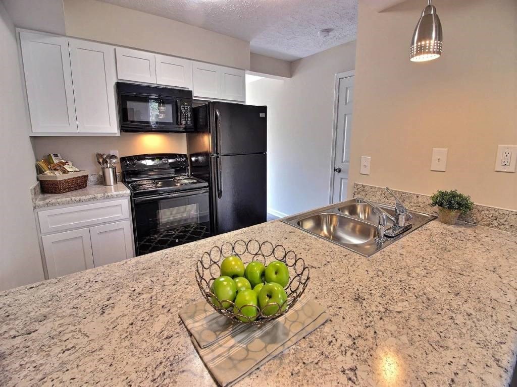 a kitchen with black appliances and a bowl of fruit