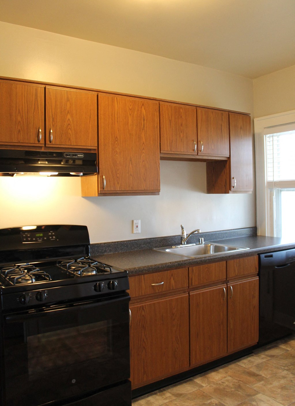 A kitchen with a black stove and wooden cabinets.
