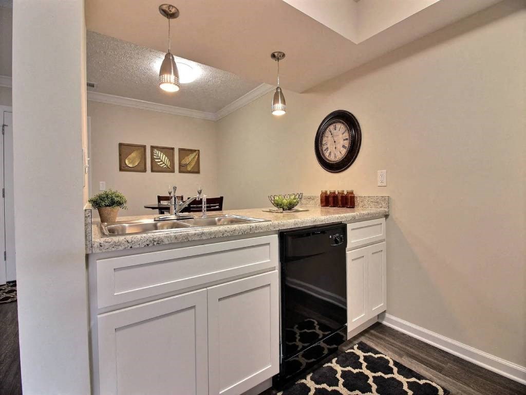 a kitchen with a sink and a dishwasher and a clock