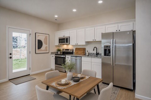 A modern kitchen with a dining table set for two.