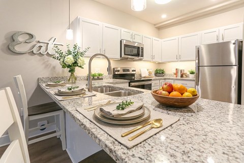 A modern kitchen with granite countertops and stainless steel appliances.