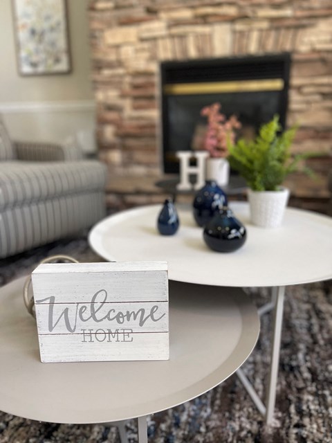 a white coffee table with a welcome home sign in a living room with a fireplace