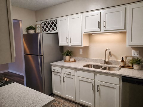 A kitchen with white cabinets and a stainless steel refrigerator.