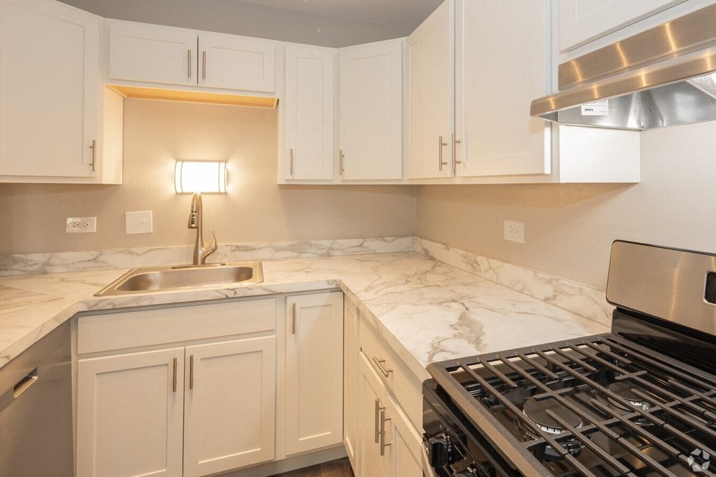 a kitchen with white cabinets and a stove and sink