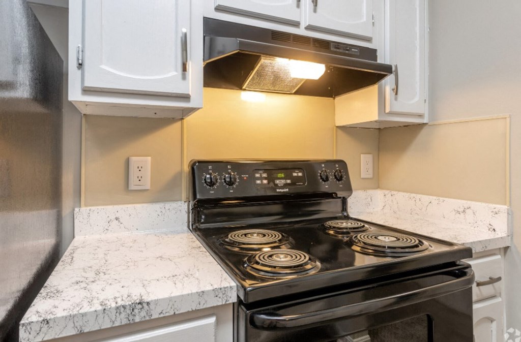 a kitchen with white cabinets and a stove and microwave