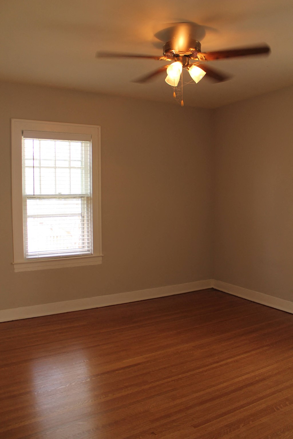 an empty room with a ceiling fan and a window