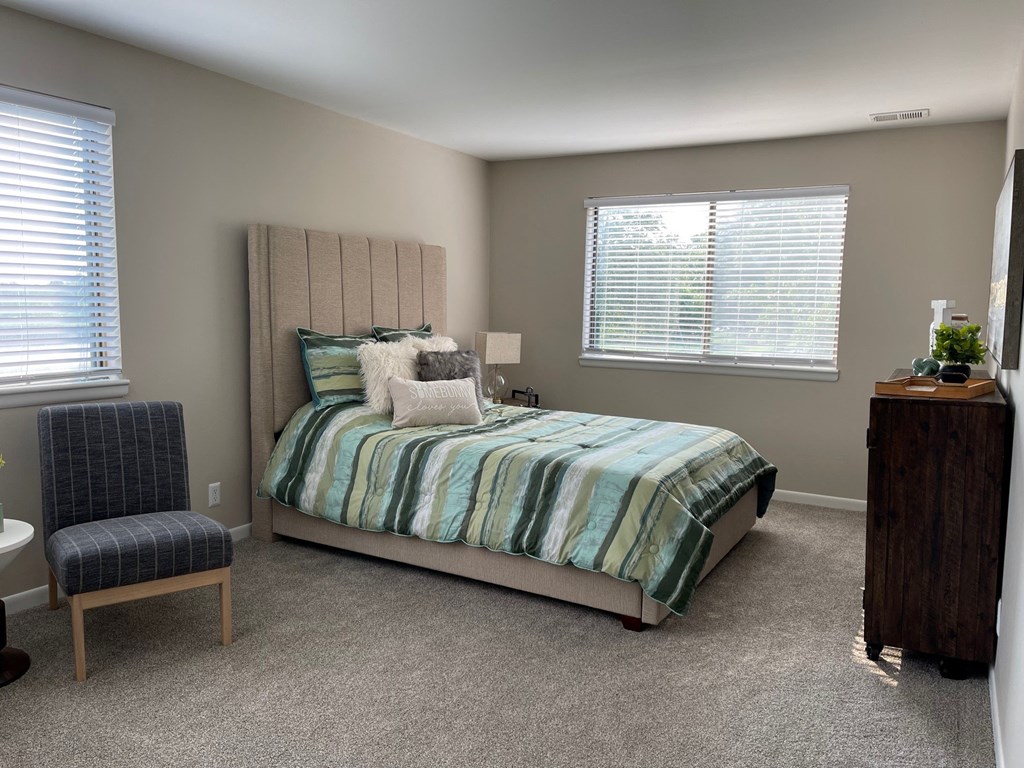 a bedroom with a bed and a chair and a window