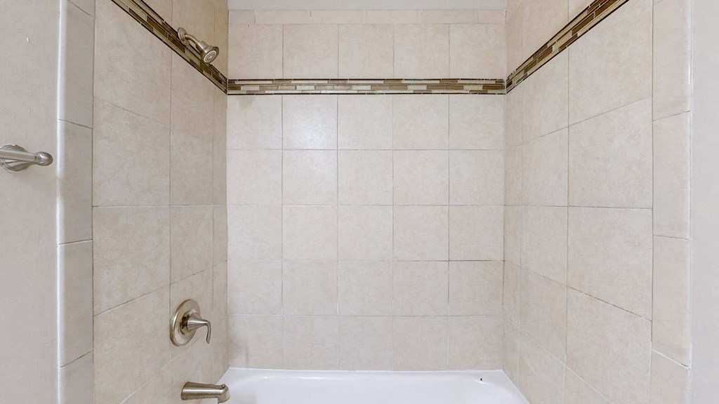 a white tiled bathroom with a shower and a sink