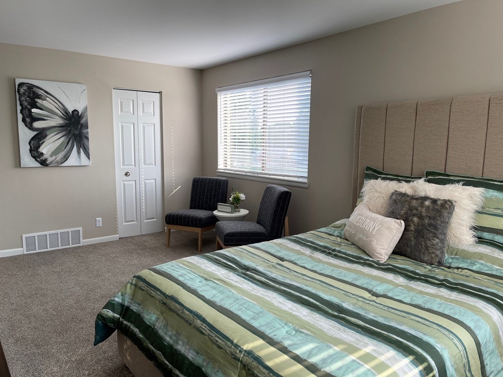 a bedroom with a bed and a chair and a window