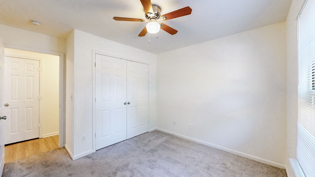 a bedroom with white walls and a ceiling fan
