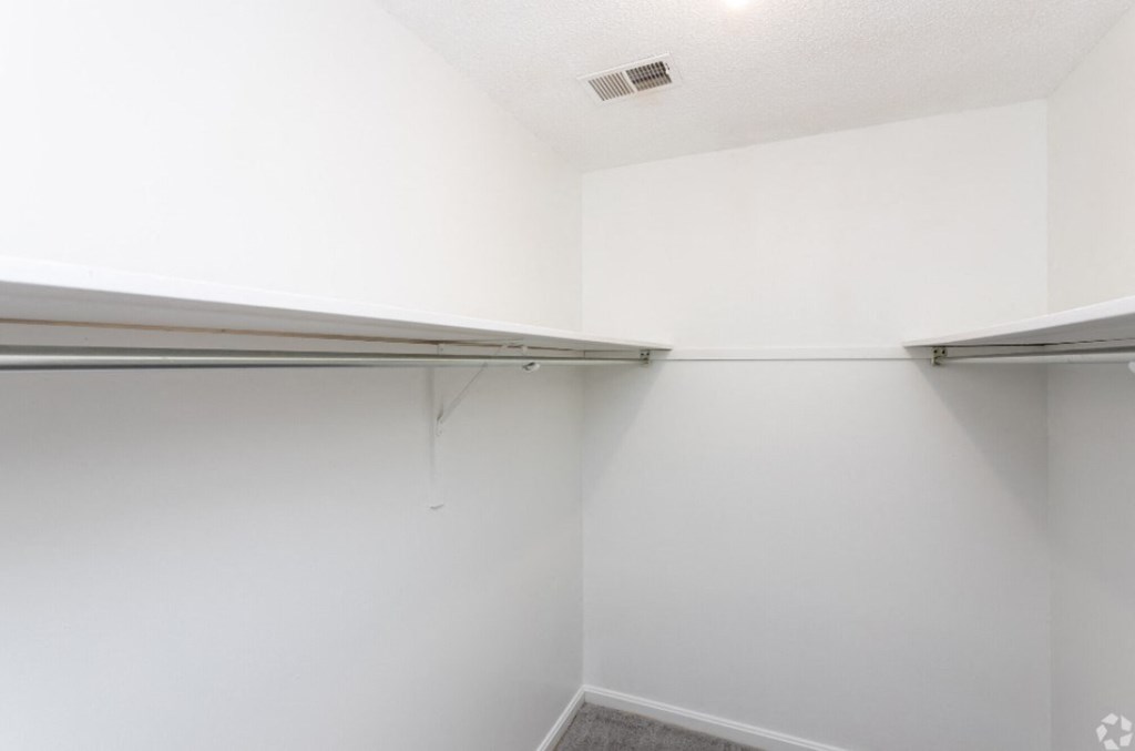 an empty closet in a room with white walls and a silver hangar
