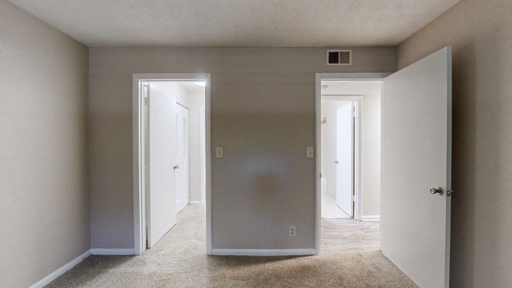 an empty living room with white walls and a door to a hallway