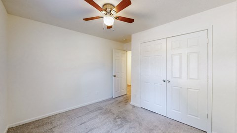 a bedroom with two closets and a ceiling fan