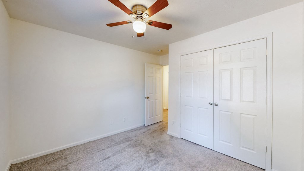 a bedroom with two closets and a ceiling fan