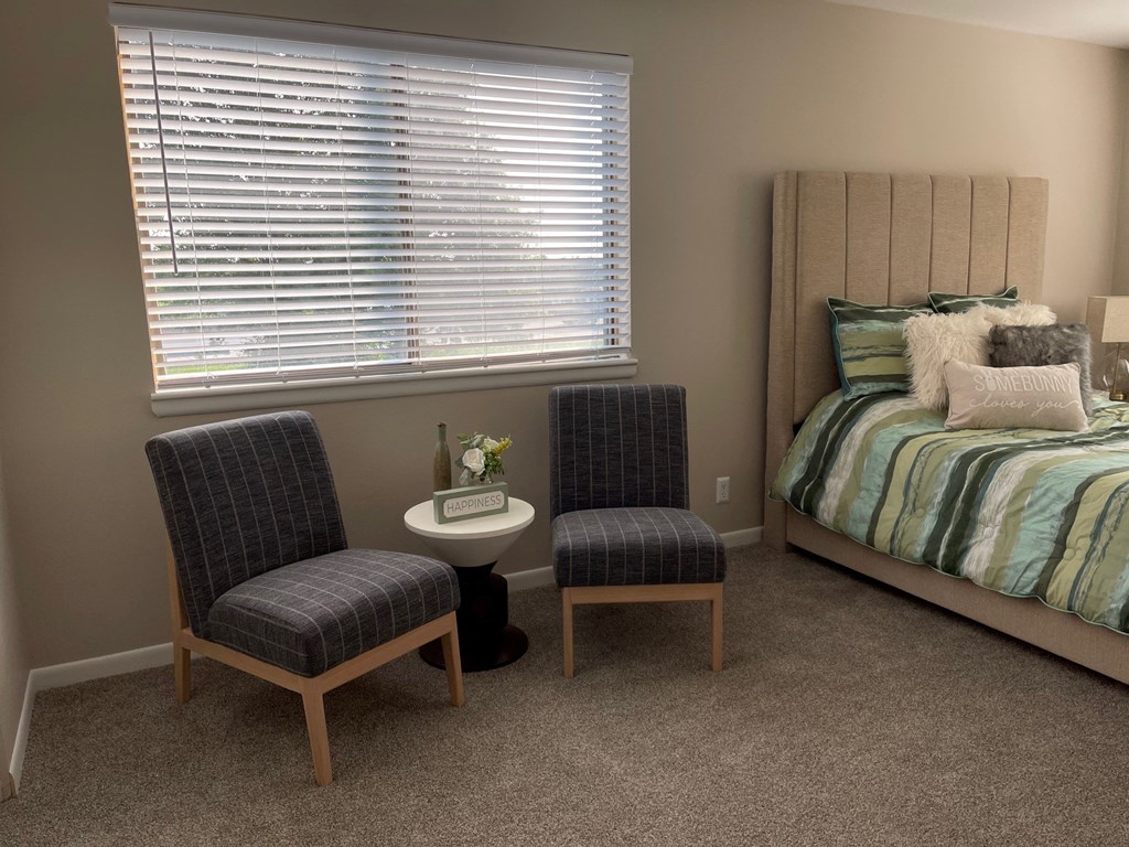 a bedroom with a bed and two chairs and a table