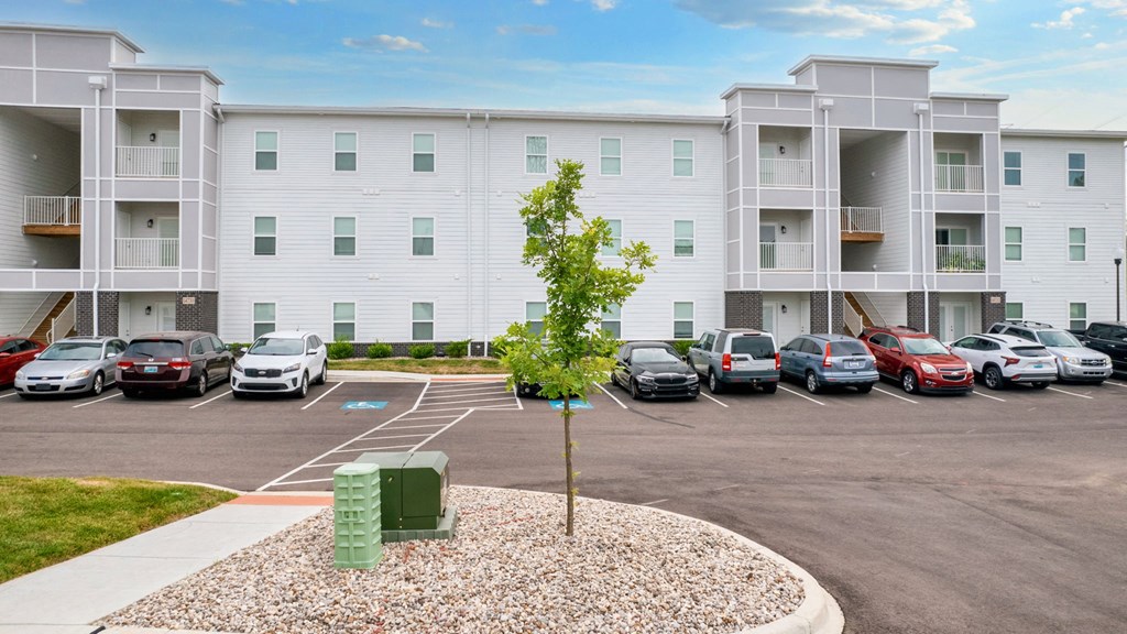 an empty parking lot with cars in front of an apartment building