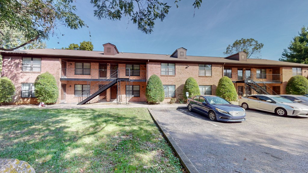 the front of a brick apartment building with cars parked in front