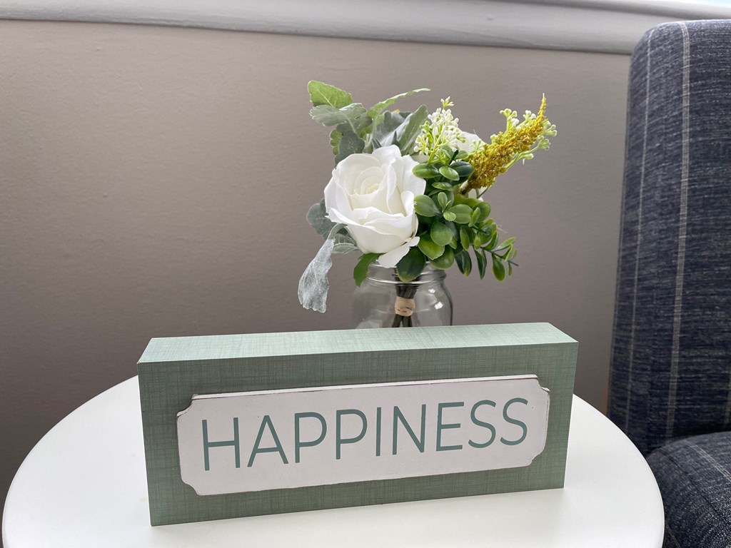 a vase of flowers on a table with a sign that says happiness