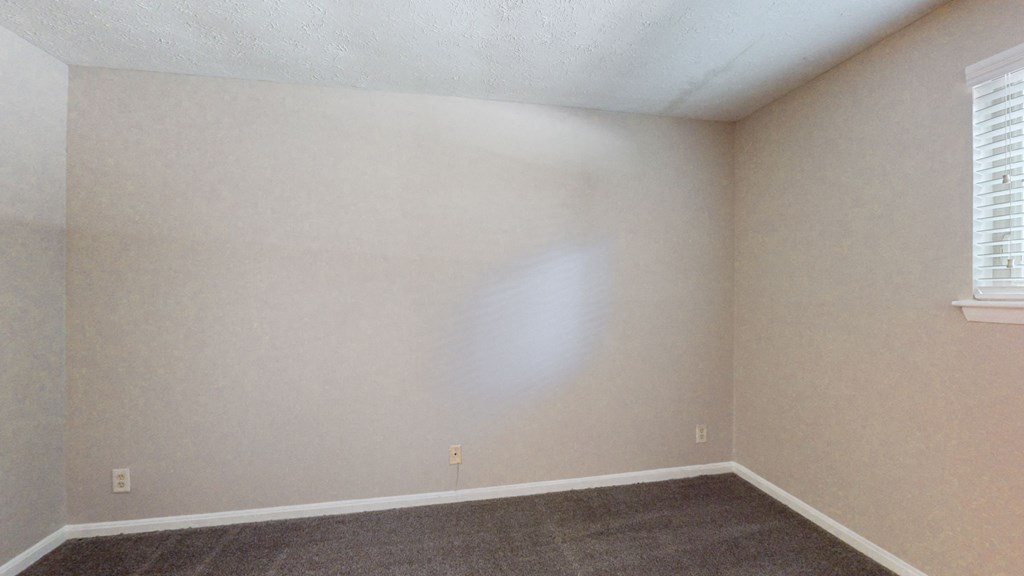 an empty room with a carpet and white walls