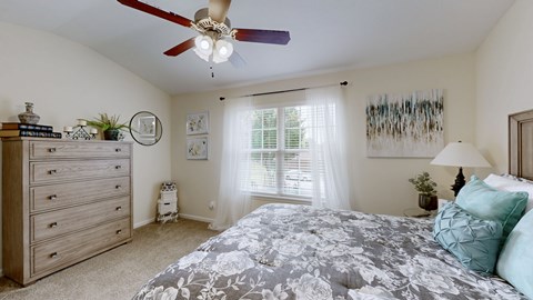 A bedroom with a large bed and a ceiling fan.