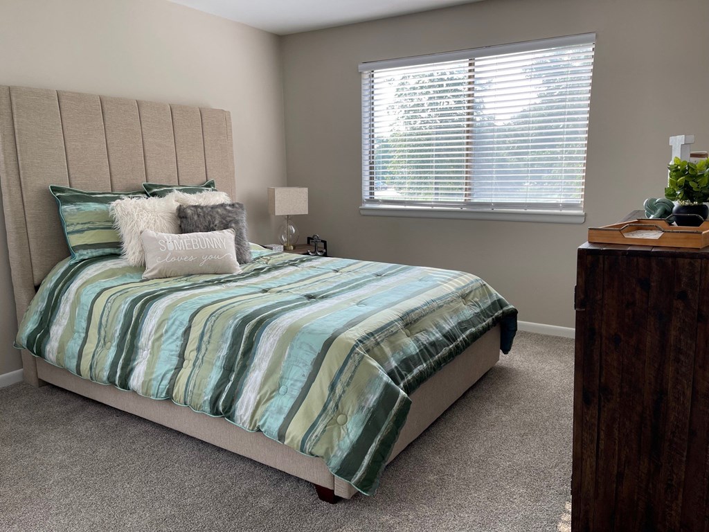 a bedroom with a bed and a dresser and a window