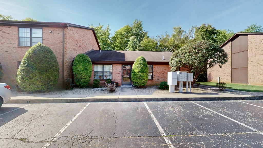 an empty parking lot in front of a brick house