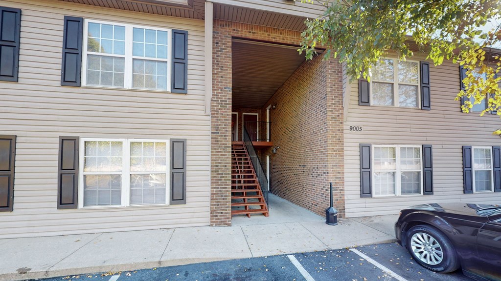 the front of a house with stairs and a car parked in front