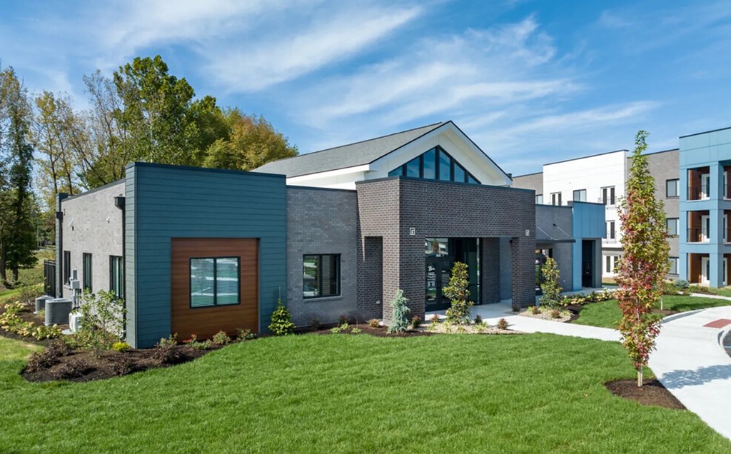 A modern house with a blue door and a green lawn.