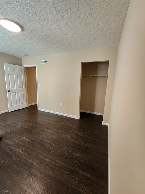 A room with a white door and a brown door with a brown floor.
