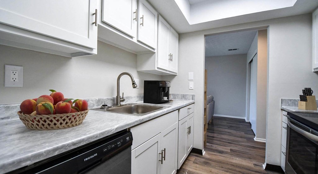 a kitchen with white cabinets and a bowl of fruit on the counter