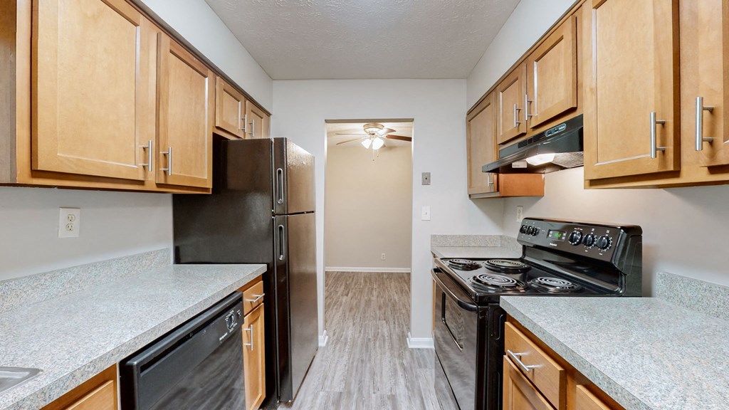 an empty kitchen with wood cabinets and black appliances