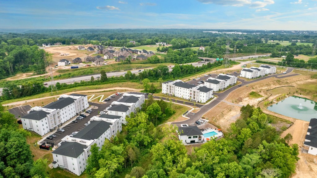 an aerial view of an apartment complex with a pool and trees