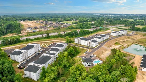 an aerial view of an apartment complex with a pool and trees