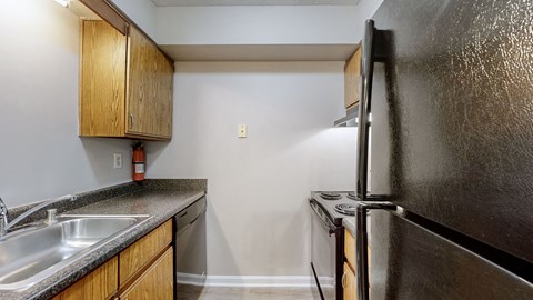 A black refrigerator sits next to a sink in a kitchen.