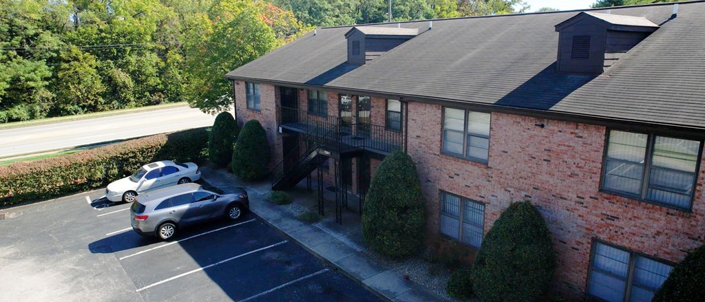 an aerial view of a brick house with cars parked in a parking lot