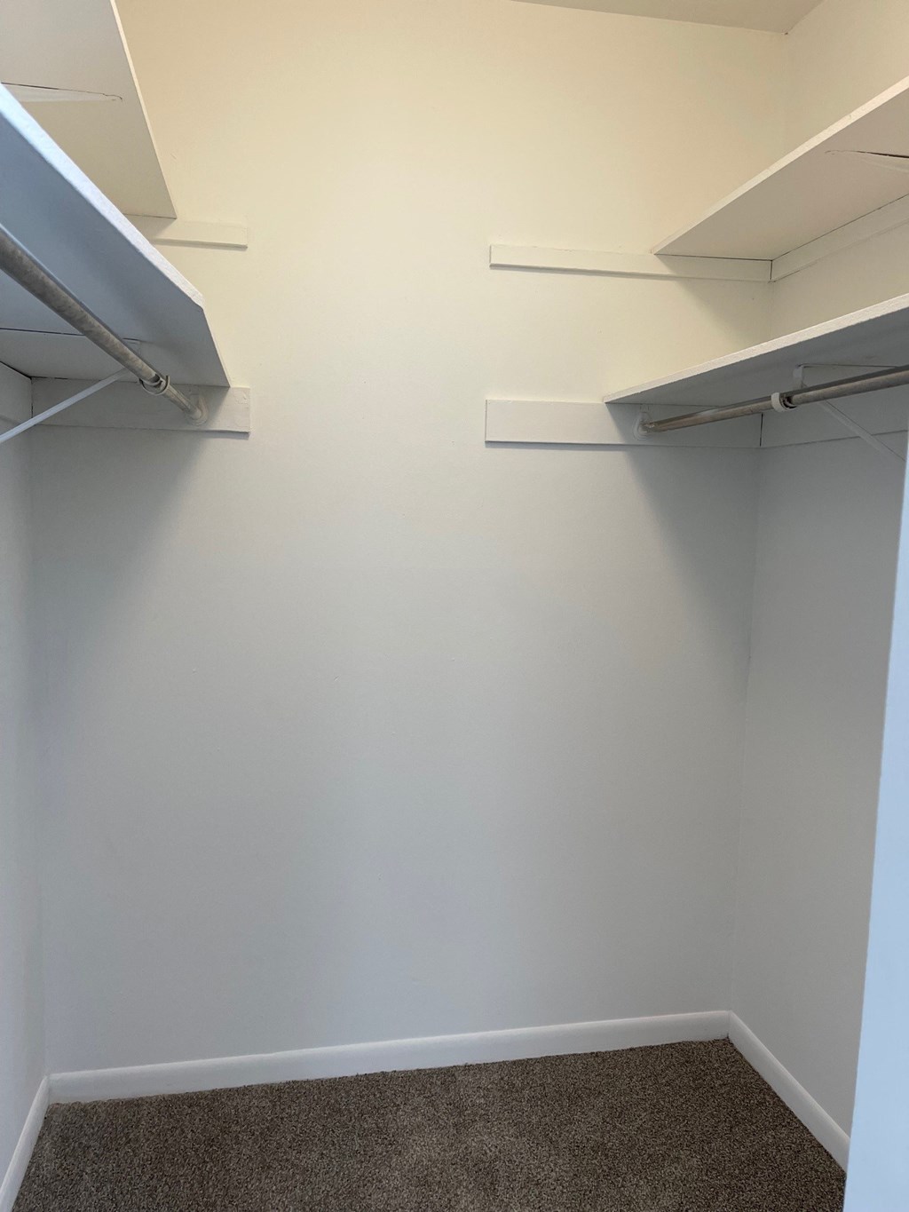 a walk in closet with two shelves on the wall