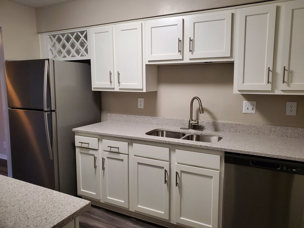 A kitchen with white cabinets and a black refrigerator.
